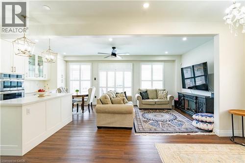 Open-concept living area with wood-finish flooring, white cabinetry, integrated double ovens, and recessed lighting - 122 Iron Gate Street, Kitchener, ON - Indoor