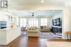 Open-concept living area with wood-finish flooring, white cabinetry, integrated double ovens, and recessed lighting - 