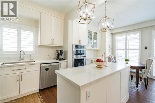 Bright, open-concept kitchen featuring crisp white cabinetry with brushed metal hardware, white quartz countertops, and a generously proportioned island with seating - 122 Iron Gate Street, Kitchener, ON - Indoor