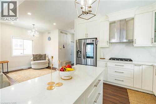 White shaker cabinetry, stainless steel appliances, a kitchen island with stone countertop, wood-finish flooring, and recessed lighting - 122 Iron Gate Street, Kitchener, ON - Indoor Photo Showing Kitchen With Upgraded Kitchen