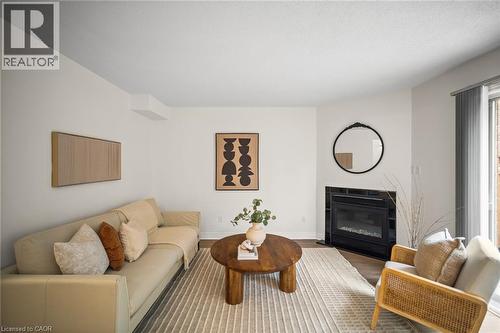 Fireplace with black tile surround, wood-finish flooring, white walls, and sliding glass door - 320 Hamilton Drive Unit# 10, Ancaster, ON - Indoor Photo Showing Living Room With Fireplace