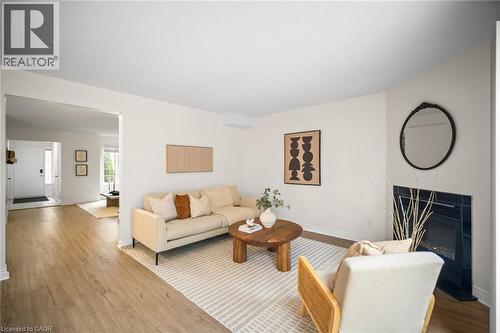 Light wood-finish flooring throughout, a fireplace with a dark tile surround, and a white interior door - 320 Hamilton Drive Unit# 10, Ancaster, ON - Indoor Photo Showing Living Room With Fireplace