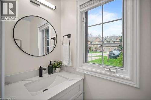White cabinetry with integrated sink, black matte faucet, and round framed mirror - 320 Hamilton Drive Unit# 10, Ancaster, ON - Indoor Photo Showing Bathroom