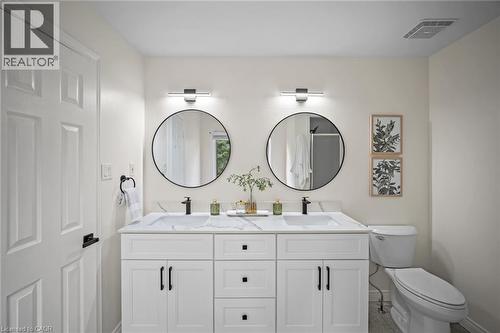 Dual vanity with white cabinetry, integrated sinks, black hardware, and round frameless mirrors - 320 Hamilton Drive Unit# 10, Ancaster, ON - Indoor Photo Showing Bathroom