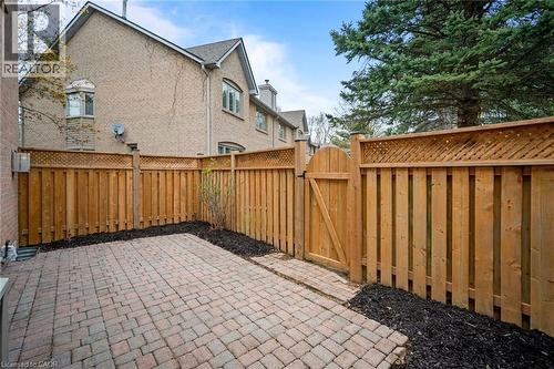 Paved patio with brick pavers, wood privacy fencing with lattice top, and a wood gate - 320 Hamilton Drive Unit# 10, Ancaster, ON - Outdoor With Exterior