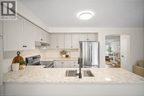 Kitchen featuring light cabinetry, stainless steel appliances, stone countertops, and an undermount sink with a matte black faucet - 320 Hamilton Drive Unit# 10, Ancaster, ON - Indoor Photo Showing Kitchen With Upgraded Kitchen
