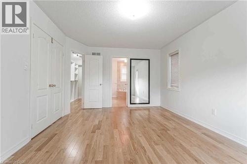Unfurnished bedroom featuring light wood-type flooring, a textured ceiling, a walk in closet, and connected bathroom - 3 Coolwater Drive Unit# Upper, Brampton, ON - Indoor Photo Showing Other Room