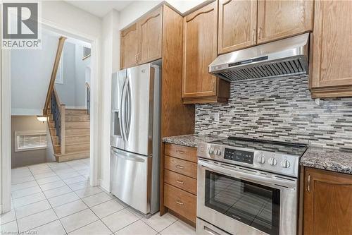 Kitchen featuring stainless steel appliances, under cabinet range hood, stone counters, light tile patterned flooring, and decorative backsplash - 3 Coolwater Drive Unit# Upper, Brampton, ON - Indoor Photo Showing Kitchen With Upgraded Kitchen