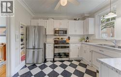 Kitchen featuring white cabinetry, stainless steel appliances, speckled countertops, and a white subway tile backsplash - 
