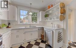 White cabinetry with silver hardware, speckled countertops, stainless steel dishwasher, and open shelving - 