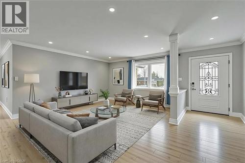 *VIRTUALLY STAGED* Recessed lighting, crown molding, wood-finish flooring, and a decorative front entry door with glass and wrought iron detailing - 44 Mcclellan Road, Alton, ON - Indoor Photo Showing Living Room