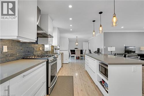 Modern kitchen with white cabinetry, stainless steel appliances, gray countertops, and a stacked stone backsplash - 44 Mcclellan Road, Alton, ON - Indoor Photo Showing Kitchen With Upgraded Kitchen