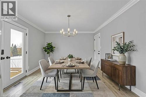 *VIRTUALLY STAGED* Crown molding, wood-finish flooring, built-in wall sconces, ceiling-mounted chandelier, and double French doors - 44 Mcclellan Road, Alton, ON - Indoor Photo Showing Dining Room