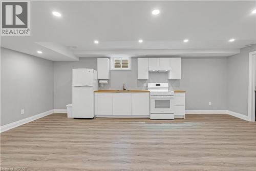 Recessed lighting, wood-finish flooring, white cabinetry, light wood-finish countertops, and a white appliance suite - 44 Mcclellan Road, Alton, ON - Indoor Photo Showing Kitchen