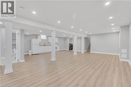 Expansive open-concept space featuring recessed lighting, wood-finish flooring, white built-in cabinetry, a built-in kitchen sink, and a full-size refrigerator - 44 Mcclellan Road, Alton, ON - Indoor