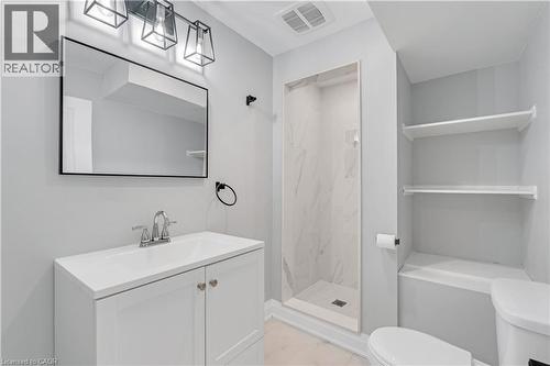 White vanity with integrated sink, chrome faucet, framed mirror, and modern three-light vanity fixture - 44 Mcclellan Road, Alton, ON - Indoor Photo Showing Bathroom