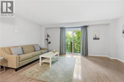 Light-filled living area featuring wood-finish flooring, white walls, and a sliding glass door - 509 Quiet Place Unit# 1, Waterloo, ON - Indoor Photo Showing Living Room