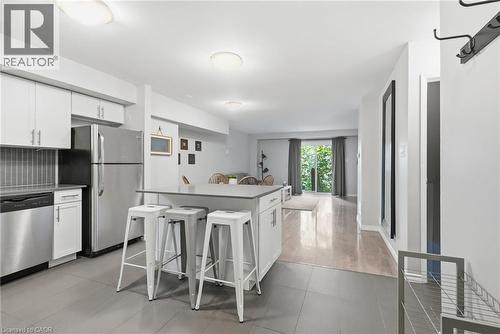 Open-concept kitchen featuring white cabinetry, stainless steel appliances, a tiled backsplash, and a central island with a solid surface countertop - 509 Quiet Place Unit# 1, Waterloo, ON - Indoor Photo Showing Kitchen