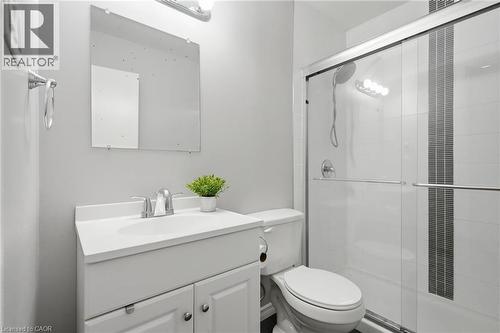 Bathroom featuring a white vanity with integrated sink, chrome faucet, wall-mounted mirror, and a shower enclosure with sliding glass doors and tiled walls - 509 Quiet Place Unit# 1, Waterloo, ON - Indoor Photo Showing Bathroom