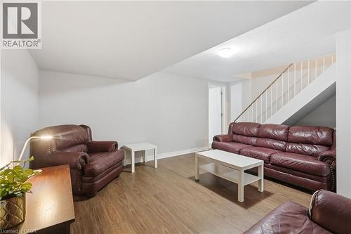 Spacious room featuring wood-finish flooring, white walls, and a staircase with white balusters - 509 Quiet Place Unit# 1, Waterloo, ON - Indoor Photo Showing Other Room