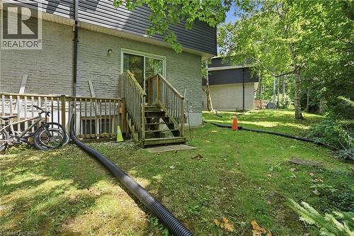 Rear exterior featuring a sliding glass door, wooden deck with stairs, and a grey brick facade - 509 Quiet Place Unit# 1, Waterloo, ON - Outdoor