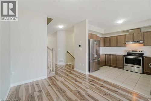 Wood-finish flooring, recessed lighting, stainless steel appliances, wood cabinetry, and tiled kitchen flooring - 70 Bradbury Road, Hamilton, ON - Indoor Photo Showing Kitchen With Stainless Steel Kitchen