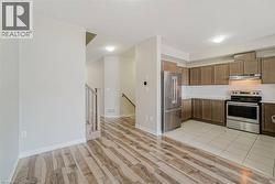 Wood-finish flooring, recessed lighting, stainless steel appliances, wood cabinetry, and tiled kitchen flooring - 