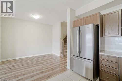 Kitchen featuring wood-finish cabinetry, stainless steel refrigerator, white subway tile backsplash, and light-colored countertops - 70 Bradbury Road, Hamilton, ON - Indoor Photo Showing Kitchen