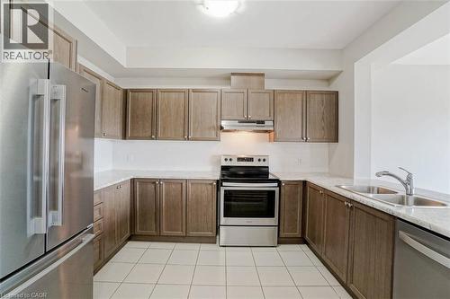Kitchen with extensive wood-finish cabinetry, light-toned countertops, and stainless steel appliances - 70 Bradbury Road, Hamilton, ON - Indoor Photo Showing Kitchen With Stainless Steel Kitchen With Double Sink