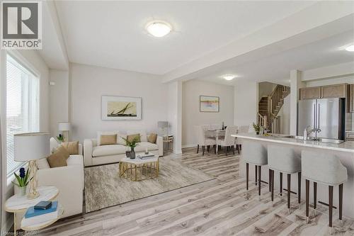 Open-concept living space with wood-finish flooring, a kitchen island with seating, stainless steel appliances, and a staircase with wood railings - 70 Bradbury Road, Hamilton, ON - Indoor