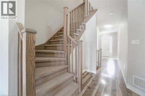 Staircase with wood-finish newel posts and handrails, carpeted treads, and light gray wall paint - 70 Bradbury Road, Hamilton, ON - Indoor Photo Showing Other Room
