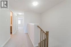 Carpeted hallway with light-toned walls and built-in ceiling lighting - 
