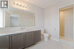 Spacious bathroom featuring a large vanity with ample counter space, built-in cabinetry, an integrated sink, and a tiled shower stall - 