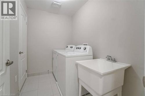 Laundry area with white appliances, utility sink, and light-toned tile flooring - 70 Bradbury Road, Hamilton, ON - Indoor Photo Showing Laundry Room