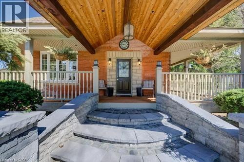 Front entrance featuring brick and stone veneer, a covered porch with a wood-plank ceiling, and a multi-level stone pathway - 875 Safari Road, Hamilton, ON 