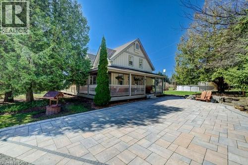 Gable roof architecture, expansive paver driveway, wraparound covered porch, mature trees, and a decorative wishing well - 875 Safari Road, Hamilton, ON 