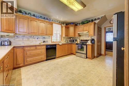 Wood cabinetry, tile backsplash, built-in range, and a patterned floor - 875 Safari Road, Hamilton, ON 