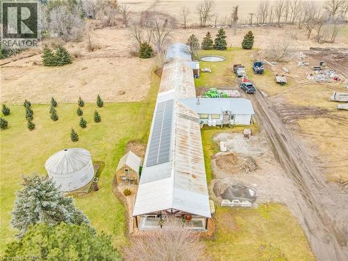 Elongated building with a corrugated metal roof, solar panel array, covered porch, and a detached silo - 875 Safari Road, Hamilton, ON 