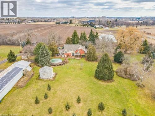 Sprawling rural property featuring a brick Colonial-style residence set on manicured grounds with mature landscaping, including evergreen and deciduous trees - 875 Safari Road, Hamilton, ON 