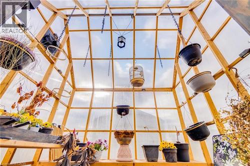Greenhouse structure with a pitched translucent roof and clear paneling, featuring a light wood frame and metal hanging chains - 875 Safari Road, Hamilton, ON 