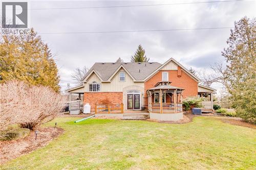 Expansive rear elevation featuring brick and siding, a covered deck, a built-in gazebo, and a manicured lawn - 875 Safari Road, Hamilton, ON 