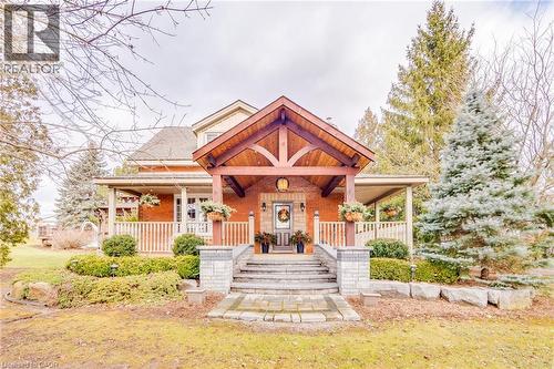 Brick facade with a prominent timber-frame portico, covered front porch, and stone-clad entry steps - 875 Safari Road, Hamilton, ON 