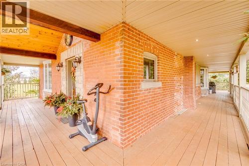 Expansive porch with wood-finish flooring, brick exterior, and a wood plank ceiling - 875 Safari Road, Hamilton, ON 