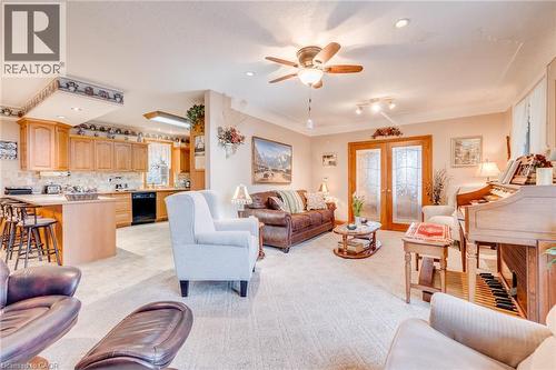 Open-concept living area with carpet flooring, wood-finish cabinetry, a breakfast bar, and glass-paneled double doors - 875 Safari Road, Hamilton, ON 