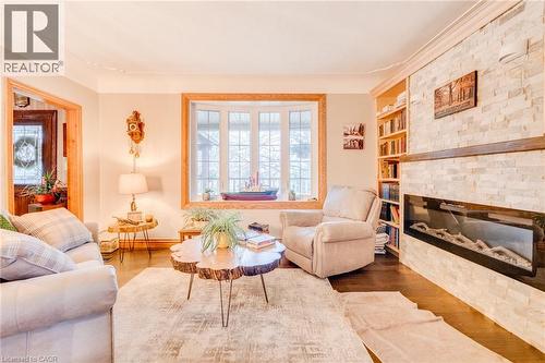 Bay window with wood trim, wood-finish flooring, stone accent wall, built-in shelving, and a linear electric fireplace - 875 Safari Road, Hamilton, ON 