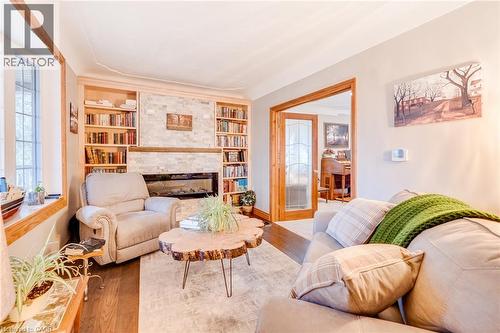 Built-in shelving, stone-clad fireplace with mantel, hardwood flooring, bay window, and glass-paneled French doors - 875 Safari Road, Hamilton, ON 