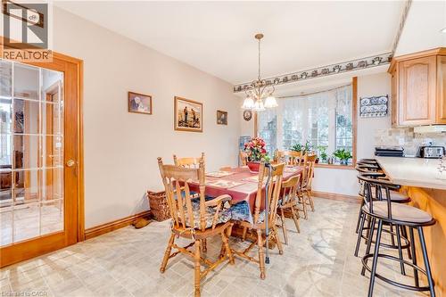 Spacious dining area featuring a bay window, tile flooring, pendant lighting, and an adjacent breakfast bar with bar seating - 875 Safari Road, Hamilton, ON 