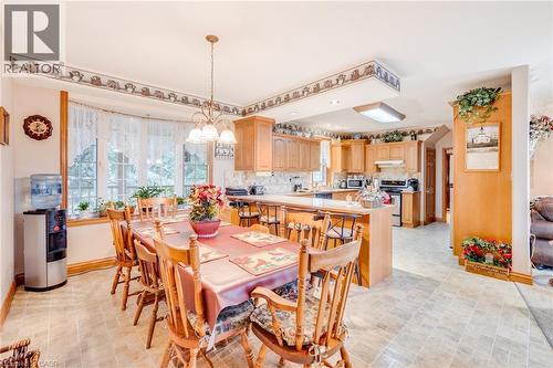 Open-concept kitchen and dining area featuring light wood cabinetry, a bay window, and tiled flooring - 875 Safari Road, Hamilton, ON 