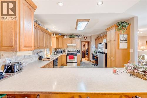 Kitchen featuring wood cabinetry, light-toned countertops, and stainless-steel appliances - 875 Safari Road, Hamilton, ON 