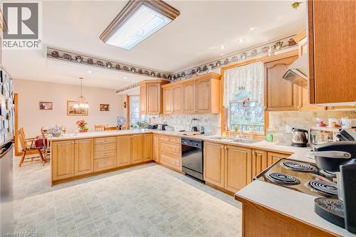 Spacious kitchen with wood-finish cabinetry, light-toned countertops, a built-in electric range, and a built-in dishwasher - 875 Safari Road, Hamilton, ON 
